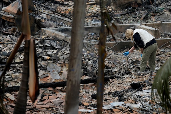 A resident sifts through their fire-damage property after the Franklin Fire swept through, Wednesday, Dec. 11, 2024, in Malibu, Calif. (AP Photo/Damian Dovarganes)