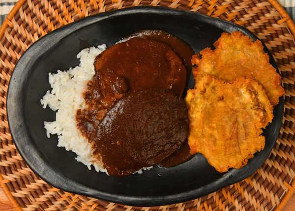 Posta Negra Cartagenera (beef roast in the manner of the city of Cartagena) is served here with rice and Fried Green Plantains. “New Year’s Eve is a big holiday in Colombia and, as in many cultures, serving a roast is the sign of a special meal," chef Christian Lopez said. (Styling by Christian Lopez / Chris Hunt for the AJC)