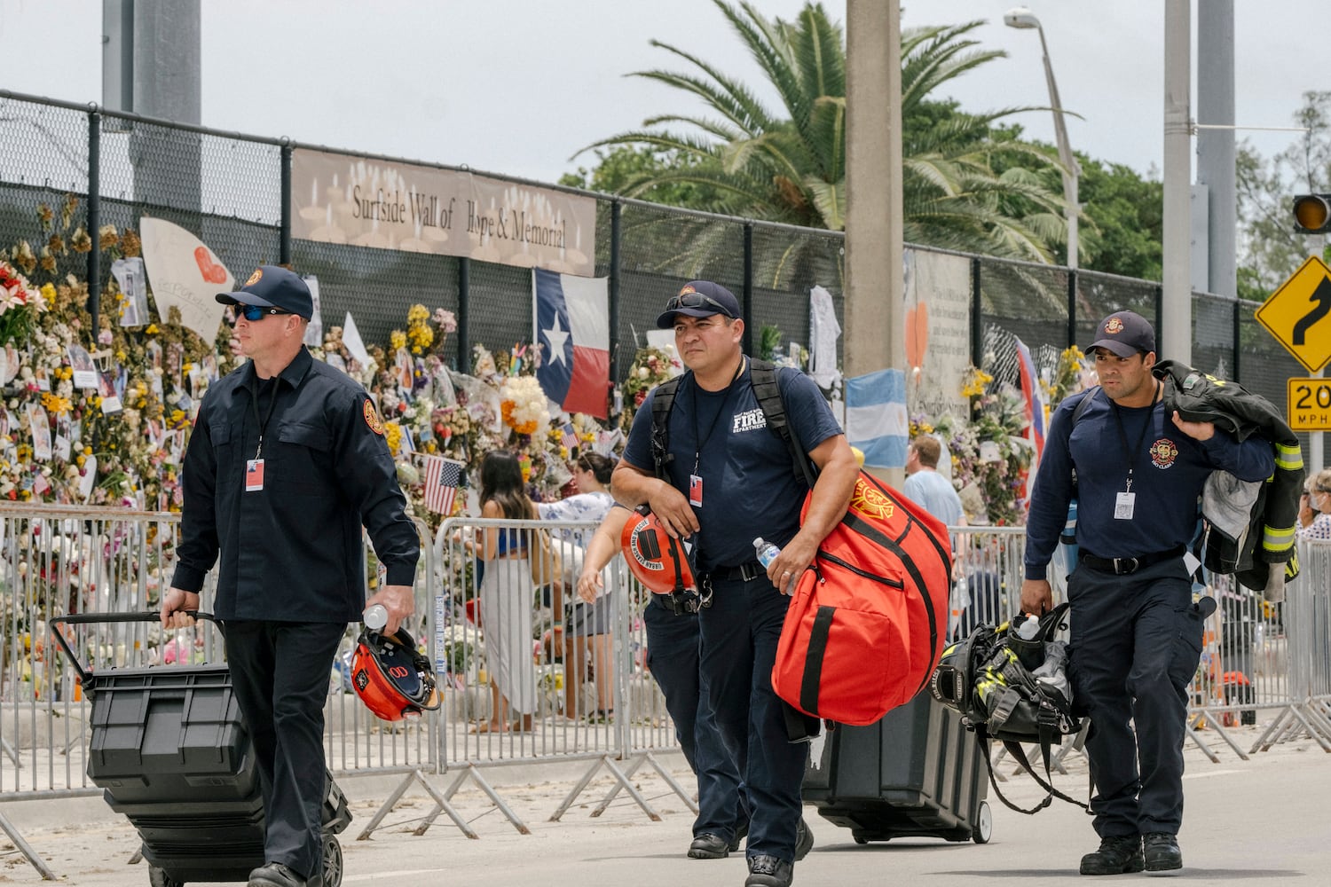 Search and rescue workers walk near a memorial to victims of the Champlain Towers South condo building in Surfside, Fla., on Monday, July 5, 2021. (Mark Abramson/The New York Times)