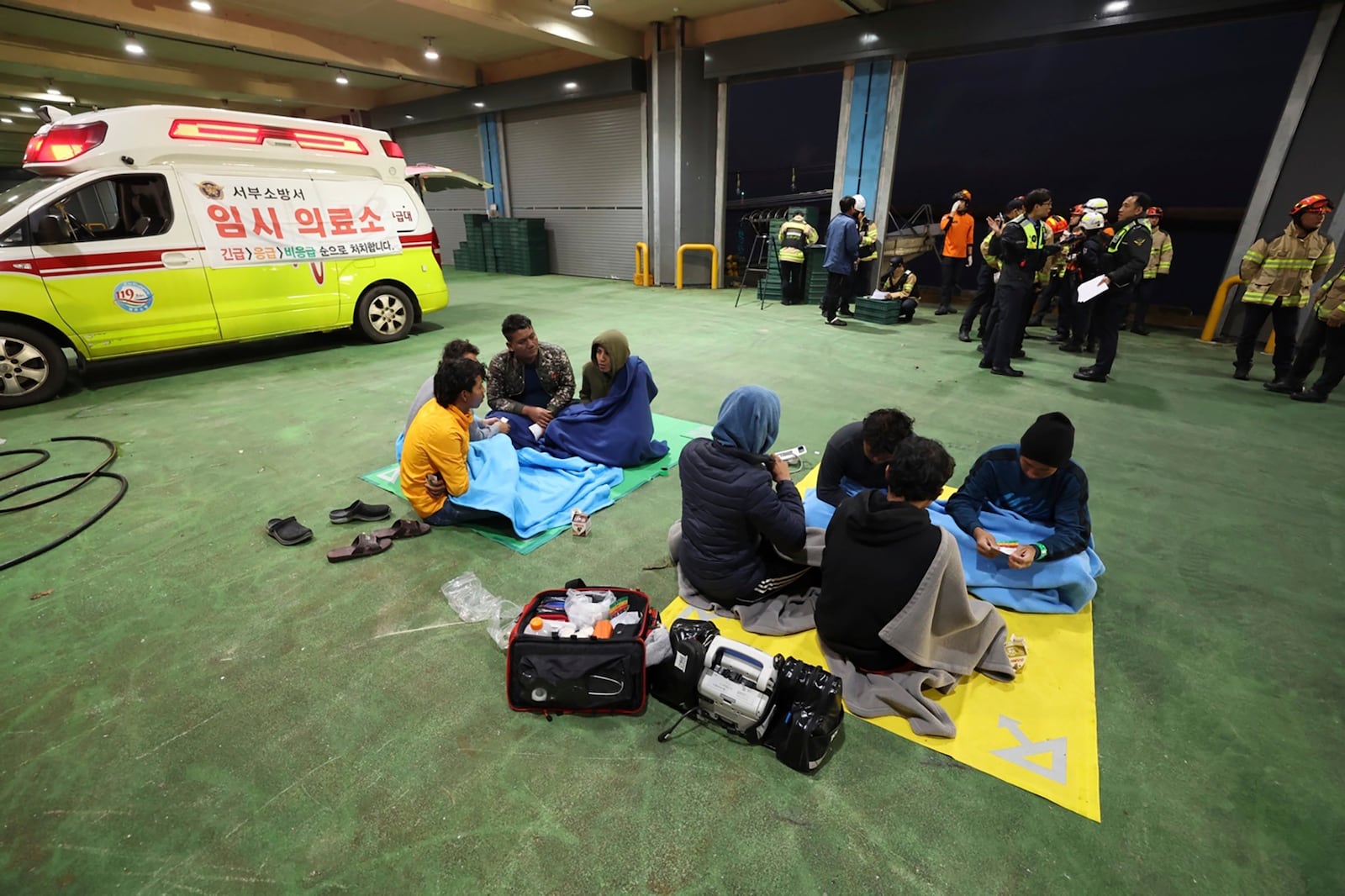 Rescued crew members of a fishing boat wait for transfer to a hospital at a port on Jeju Island, South Korea, Friday, Nov. 8, 2024. (Park Ji-ho/Yonhap via AP)