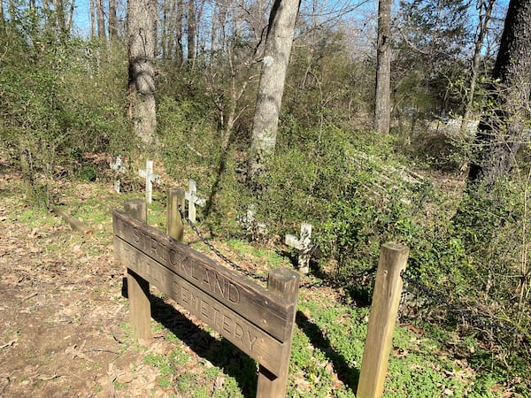 Today, on a small patch of land in a large wooded backyard near the Forsyth and Gwinnett border, six small white crosses mark the resting place of Strickland family members. (Adrianne Murchison / adrianne.murchison@ajc.com)