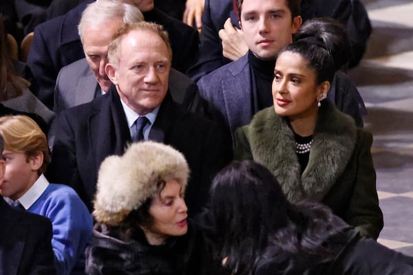 FILE - Actress Salma Hayek and her husband CEO of Kering Francois-Henri Pinault sit inside Notre Dame Cathedral before France's iconic cathedral is formally reopening its doors for the first time since a devastating fire nearly destroyed the 861-year-old landmark in 2019, Saturday Dec.7, 2024 in Paris. (Ludovic Marin/Pool via AP, File)