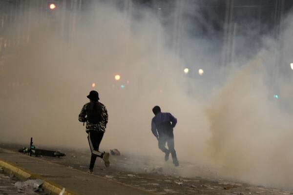 People run to avoid tear gas during clashes with riot police, as the Greek opposition parties have challenged the country's center-right government with a censure motion in parliament over a devastating rail disaster nearly two years ago, in Athens, Wednesday, March 5, 2025. (AP Photo/Petros Giannakouris)