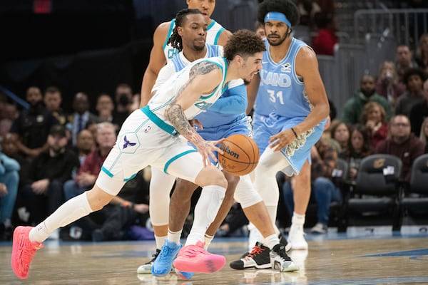 Charlotte Hornets' LaMelo Ball, front, drives past Cleveland Cavaliers' Darius Garland, center, and Jarrett Allen (31) during the first half of an NBA basketball game in Cleveland, Sunday, Nov 17, 2024. (AP Photo/Phil Long)