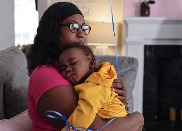 Heather Cooper sits with her sleepy son at Auntie Angie's house.  (Natrice Miller/ natrice.miller@ajc.com)