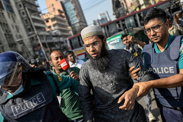 Policemen detain a supporter of the banned Islamist group Hizbut Tahrir during a march near Baitul Mokarram Mosque in Dhaka, Bangladesh, Friday, March 7, 2025. (AP Photo/Mahmud Hossain Opu)