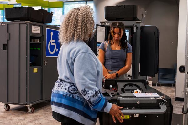 A woman receives instructions from a volunteer on how to properly discard her ballot receipt at the polling station, Thursday, Oct. 31, 2024, in Atlanta. (AP Photo/Jason Allen)