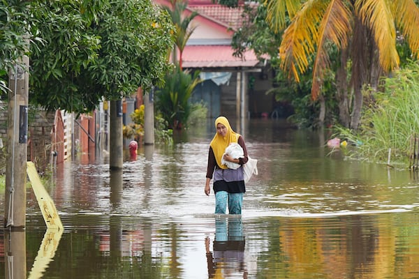 A woman wades through floodwater in Tumpat, on the outskirts of Kota Bahru in Kelantan state on the east coast of Malaysia, Tuesday, Dec. 3, 2024. (AP Photo/Vincent Thian)