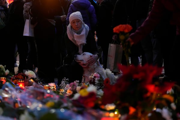 Citizens pay tribute for deaths outside St. John's Church near a Christmas Market, where a car drove into a crowd on Friday evening, in Magdeburg, Germany, Saturday, Dec. 21, 2024. (AP Photo/Ebrahim Noorozi)