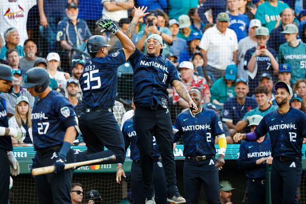 National League catcher Elias Diaz of the Colorado Rockies, left, high fives infielder Orlando Arcia after Diaz’ 2-run  homer in the 8th inning that put the National League up 3-2 during the 2023 MLB All-Star Game July 11, 2023, at T-Mobile Park, in Seattle. (Dean Rutz/The Seattle Times/TNS)