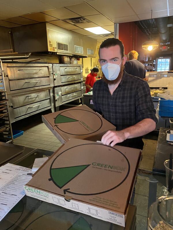 O4W Pizza’s Fraser Cody fetches pizza pies for a takeout customer. Wendell Brock for The Atlanta Journal-Constitution