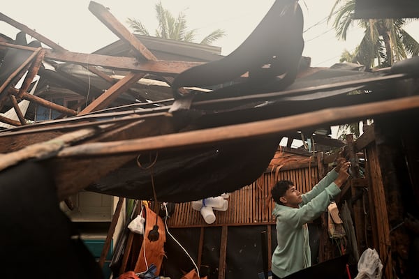 A resident checks belongings from his damaged home that was blown off by strong winds caused by Typhoon Man-yi in the municipality of Baler, Aurora province, northeastern Philippines Monday, Nov. 18, 2024. (AP Photo/Noel Celis)