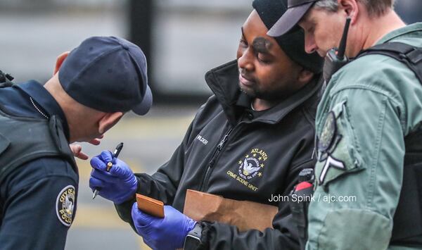 Atlanta police investigators examine a shell casing found near the Varsity early Tuesday morning after a man was shot in the parking lot. JOHN SPINK / JSPINK@AJC.COM