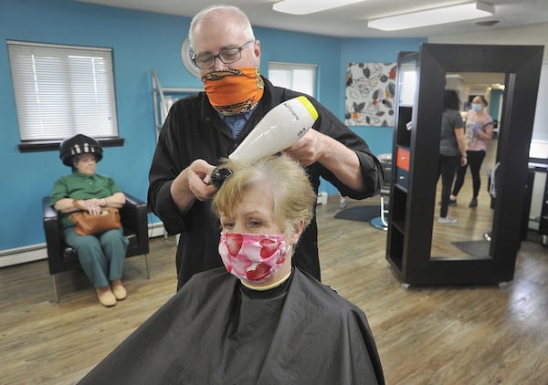 Chuck Deskins, owner of Guys and Dolls Family Salon in Tipp City, dries the the hair of Candy Schlieper. MARSHALL GORBYSTAFF