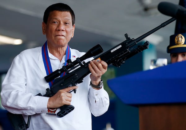 FILE - Philippine President Rodrigo Duterte jokes to photographers as he holds an Israeli-made Galil rifle at Camp Crame in suburban Quezon city northeast of Manila, Philippines on April 19, 2018. (AP Photo/Bullit Marquez, File)