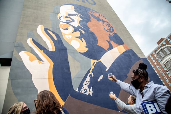 People raise a glass of champagne to the John Lewis mural after the election was called for Joe Biden Saturday, Nov. 7, 2020 in Atlanta, Georgia. (Steve Schaefer/Atlanta Journal-Constitution/TNS)