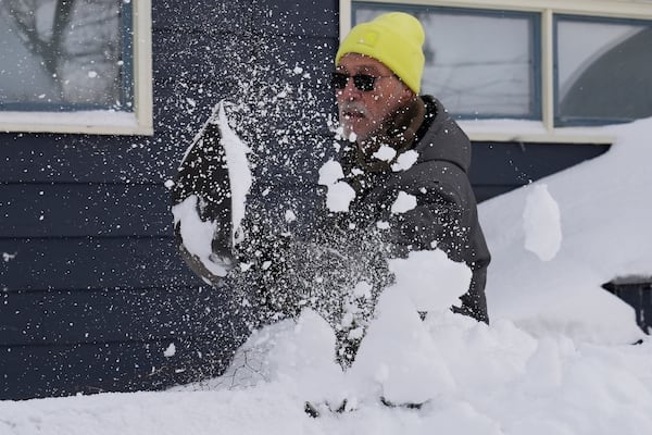 Ron Colby clears snow from a dog run at his home, Monday, Dec. 2, 2024, in Geneva-on-the-Lake, Ohio. (AP Photo/Sue Ogrocki)