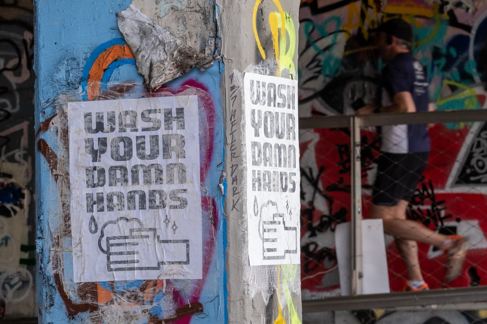 A runner heads into the Krog Street tunnel Friday morning March 20, 2020 past signs that remind people to practice proper hygiene. Ben@BenGray.com  for the Atlanta Journal-Constitution