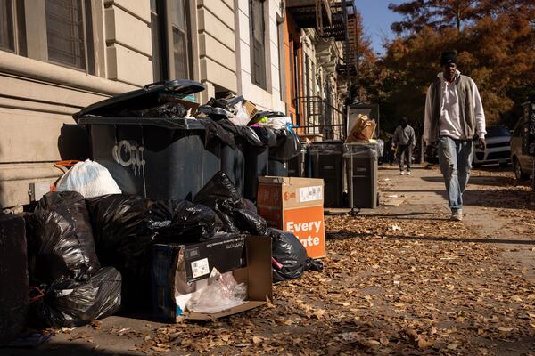 A person walks next to the pile of trash, Friday, Nov. 15, 2024, in the Brooklyn borough of New York. (AP Photo/Yuki Iwamura)