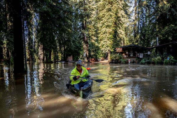 John Phillips, front, and neighbor Kevin Ozorkiewicz row a canoe at the flooded Mirabel RV Park & Campground after a major storm in Forestville, Calif., Saturday, Nov. 23, 2024. (Stephen Lam/San Francisco Chronicle via AP)