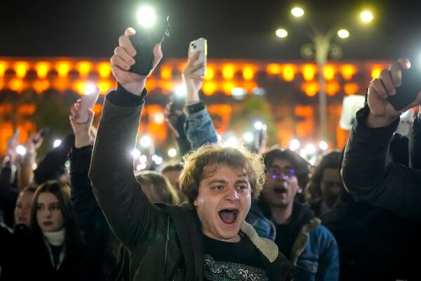 Youngsters shout slogans and flash the light of their mobile phones in Bucharest, Romania, Wednesday, Nov. 27, 2024, during a protest against Calin Georgescu, the independent candidate for Romanian presidency who won the first round of elections making it to the Dec. 8, runoff. (AP Photo/Vadim Ghirda)