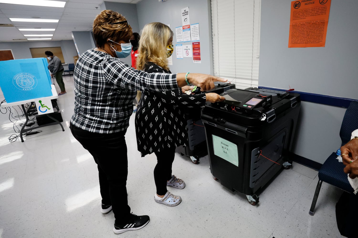 A pool worker indicates the next step to Kathy McClure during the first day of early voting of the general elections on Monday, October 17, 2022. Miguel Martinez / miguel.martinezjimenez@ajc.com