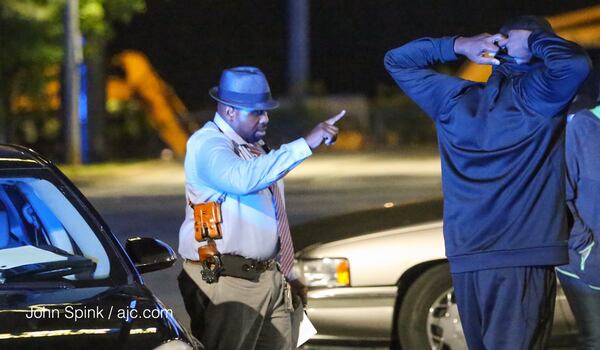 Detectives talked with concerned parties at the scene  of the shooting. JOHN SPINK / JSPINK@AJC.COM