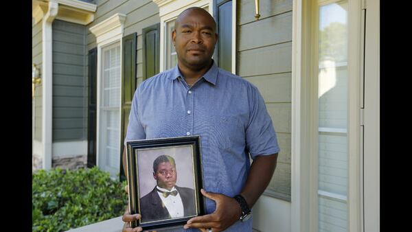               In this June 14, 2019 photo, Chris Parks poses with a portrait of his brother Donovan Corey Parks in Powder Springs, Ga.  (AP Photo/Andrea Smith)