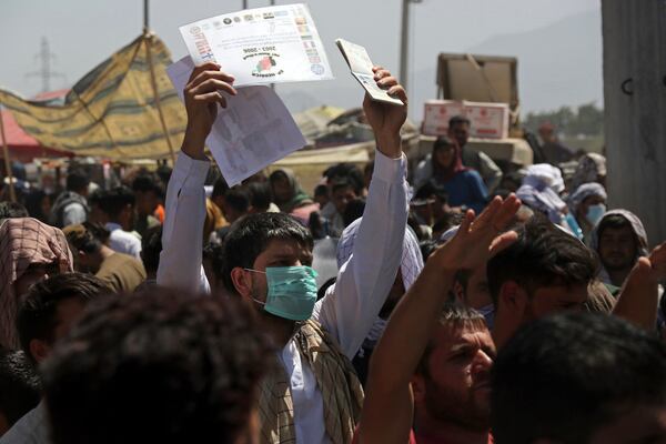 Hundreds of people gathered, some holding documents, near an evacuation control checkpoint on the perimeter of the Hamid Karzai International Airport, in Kabul, Afghanistan, on Aug. 26.  (AP Photo/Wali Sabawoon)