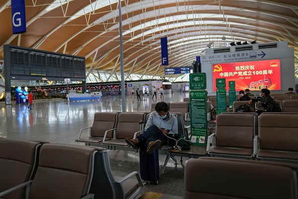 FILE - Passengers wearing face masks to help protect against the coronavirus take rest at Pudong International Airport in Shanghai, China on July 25, 2021. Delta Air Lines said Monday, Dec. 27, 2021, that new cleaning requirements at a Shanghai airport were behind the decision to turn back a recent flight from Seattle in mid-air, a move that had prompted a protest from the Chinese consulate in San Francisco. (AP Photo/Andy Wong, File)