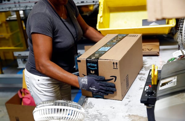 FILE- In this Aug. 3, 2017, file photo, Myrtice Harris applies tape to a package before shipment at an Amazon fulfillment center in Baltimore. Amazon is boosting its minimum wage for all U.S. workers to $15 per hour starting next month. The company said Tuesday, Oct. 2, 2018, that the wage hike will benefit more than 350,000 workers, which includes full-time, part-time, temporary and seasonal positions. (AP Photo/Patrick Semansky, File)