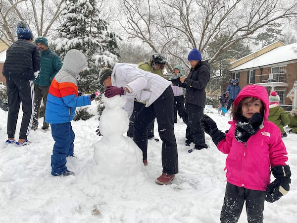 Four-year-old Jane Winnie Lewis, right, helps collect snowman parts at the Lullwater Parc community in Druid Hills on the morning of Dec. 10, 2025. (Pete Corson/AJC)