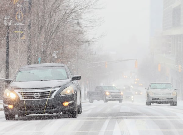 Cars start sliding on Centennial Olympic Park Drive in downtown Atlanta as snow covers the street Tuesday.