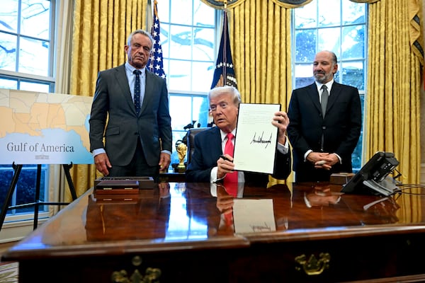 President Donald Trump holds a signed executive order as Health and Human Services Secretary Robert F. Kennedy Jr., left, and Commerce Secretary Howard Lutnick watch in the Oval Office at the White House in Washington, Thursday, Feb. 25, 2025. (Pool via AP)