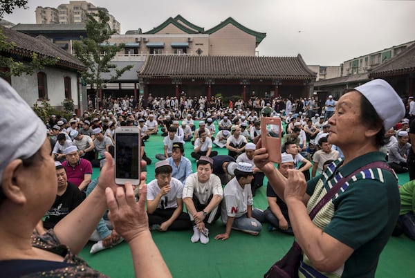 BEIJING, CHINA - JUNE 16: Chinese Hui Muslim men take photos as they wait on a carpet before Eid al-Fitr prayers marking the end of the holy fasting month of Ramadan at the historic Niujie Mosque on June 16, 2018 in Beijing, China. Islam in China dates back to the 10th century as the legacy of Arab traders who ventured from the Middle East along the ancient Silk Road. Of an estimated 23 million Muslims in China, roughly half are Hui, who are ethnically Chinese and speak Mandarin. China's constitution provides for Islam as one of five 'approved' religions in the officially atheist country though the government enforces severe limits. Worship is permitted only at state-sanctioned mosques and proselytizing in public is illegal. The Hui, one of 55 ethnic minorities in China (along with the Han majority), have long nurtured a coexistence with the Communist Party and is among the minority groups with political representation at various levels of government. The Hui Muslim population fast from dawn until dusk during Ramadan and it is believed there are more than 20 million members of the community in the country. (Photo by Kevin Frayer/Getty Images)