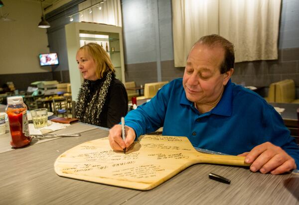 After 40 years serving the Marietta community, Kouzina Christos closed permanently Saturday, Dec. 5, 2020. Regular patrons, staff and family, including Pete Trapani, leave notes on a pizza paddle for the owner, Christos Giannes. The Greek Mediterranean restaurant closed early on Saturday but staff and regulars stayed late into the evening.  (Jenni Girtman for The Atlanta Journal-Constitution)