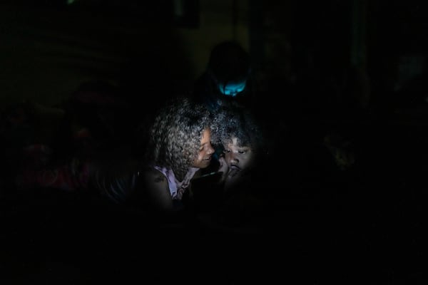 Children of Venezuelan migrants play with a cellphone in Puerto Cartí, on Panama's Caribbean coast, Saturday, Feb. 22, 2025, where they plan to take a boat to Colombia on their way back from southern Mexico after giving up hopes of reaching the U.S. amid President Trump's crackdown on migration. (AP Photo/Matias Delacroix)