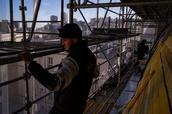 Roofers work on a building in Paris, Wednesday, Nov. 20, 2024. (AP Photo/Louise Delmotte)