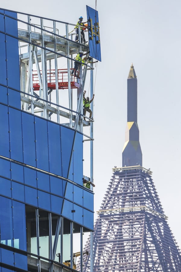 Construction workers move glass into place on the new corporate headquarters for NCR last summer. JOHN SPINK/JSPINK@AJC.COM.