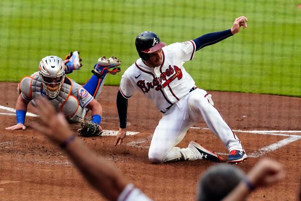 Atlanta Braves' Freddie Freeman (5) beats the tag from New York Mets catcher James McCann (33) to score on an Ozzie Albies base hit in the first inning of a baseball game Wednesday, June 30, 2021, in Atlanta. (AP Photo/John Bazemore)