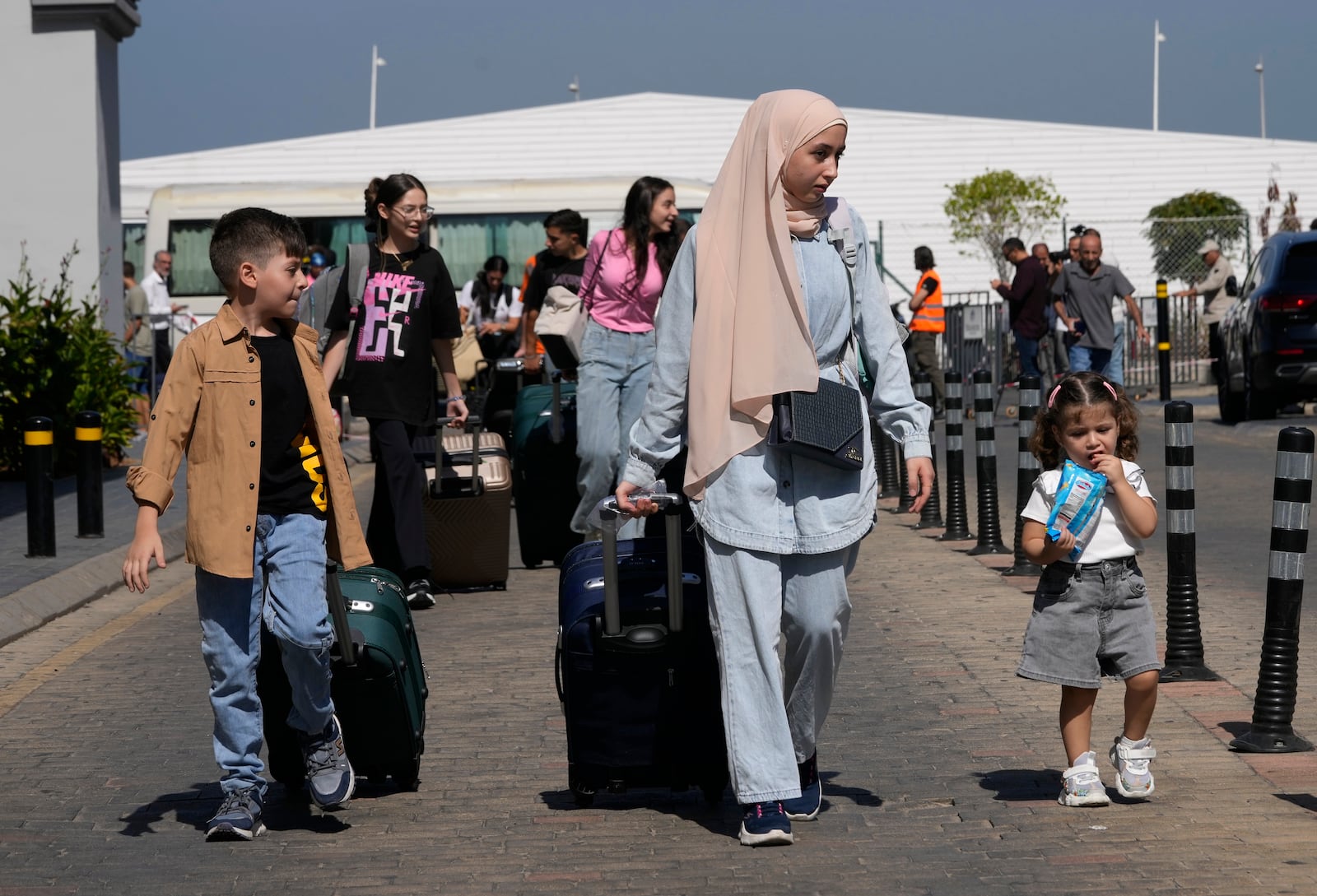 Turkish citizens carry their belongings, as they arrive at a gathering point to board a Turkish navy vessel to be evacuated to Turkey, in Beirut, Lebanon, Wednesday, Oct. 9, 2024. (AP Photo/Hussein Malla)