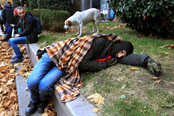 Protesters rest in a street during a rally to demand new parliamentary elections in the country, near the Parliament's building in Tbilisi, Georgia, on Monday, Nov. 25, 2024. (AP Photo/Shakh Aivazov)