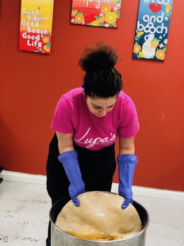 Claire Irie lifts a “scoby” (the mass of bacteria that turns tea and sugar into kombucha) from the top of the stainless steel fermenting tank. CONTRIBUTED BY LUPA’S KITCHEN