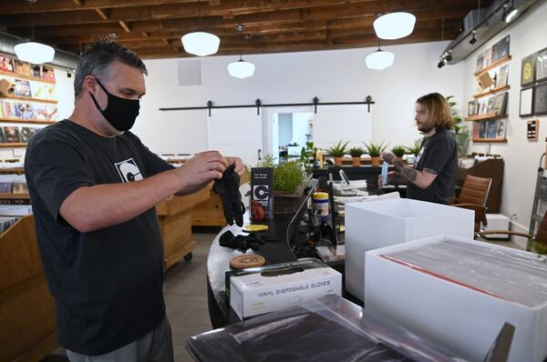 Connor Herrington (left) wears mask and latex gloves before he makes a curbside delivery at Comeback Vinyl on Friday, May 8, 2020. (Hyosub Shin / Hyosub.Shin@ajc.com)