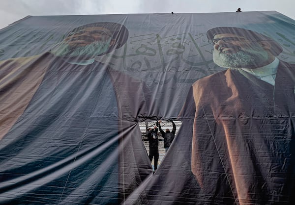 Workers display a giant banner with the portraits of the late Hezbollah leaders Sayyed Hassan Nasrallah, left, and Sayyed Hashem Safieddine, during preparation, a day ahead of their funeral procession at Beirut's City Sportive stadium, in Beirut, Lebanon, Saturday, Feb. 22, 2025. (AP Photo/Hussein Malla)