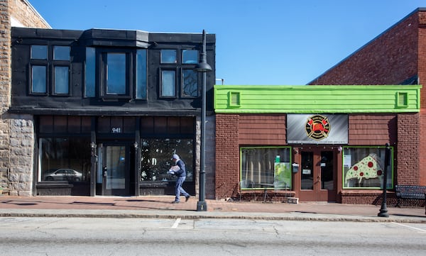   US Postal employee Melvin Daly walks past empty storefronts as he delivers mail along Main Street in Stone Mountain Tuesday, January 18, 2022.    STEVE SCHAEFER FOR THE ATLANTA JOURNAL-CONSTITUTION