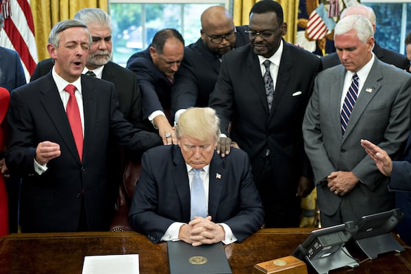 September 2017: President Donald Trump bows his head during a prayer while surrounded by U.S. Vice President Mike Pence (right), faith leaders and evangelical ministers after signing a proclamation declaring a day of prayer in the Oval Office of the White House.