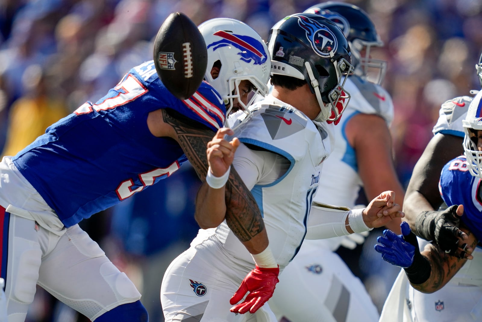 Buffalo Bills defensive end AJ Epenesa (57) strips the ball from Tennessee Titans quarterback Mason Rudolph, right, during the first half of an NFL football game Sunday, Oct. 20, 2024, in Orchard Park, N.Y. (AP Photo/Charles Krupa)