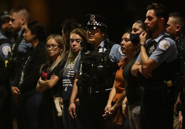 Chicago police officers watch the procession of police vehicles leading the ambulance carrying the body of a fellow officer as it arrives early Sunday at the Cook County Medical Examiner's Office.