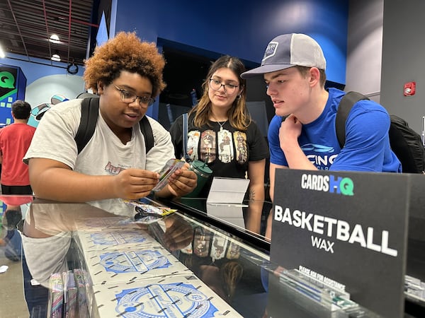 At a trade night at CardsHQ, Rosali Oshodi, 18; Emily Bueno, 17; and Maddox Wall, 17, check out Pokemon packs purchased by Oshodi. She later sold cards to rap star Waka Flocka Flame. RODNEY HO/rho@ajc.com